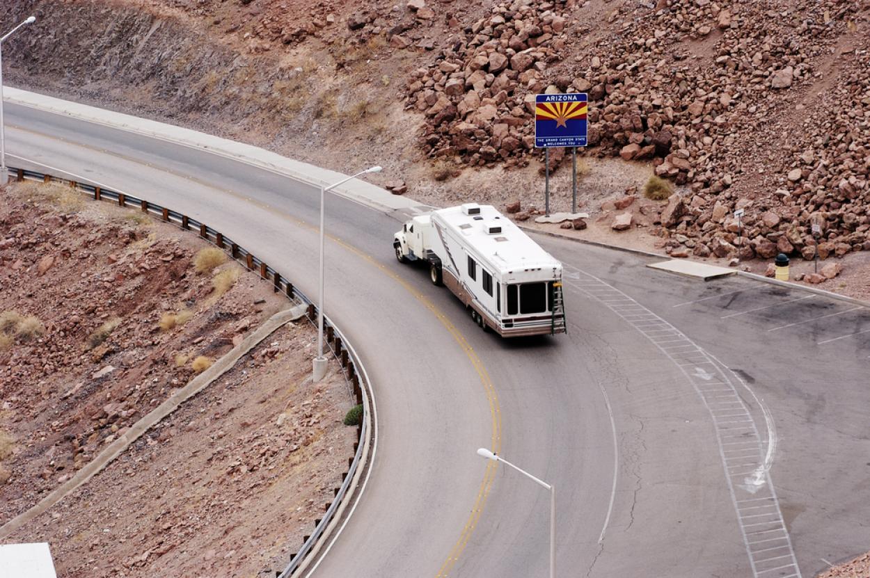 Truck tows a fifth wheel camper along a rocky road