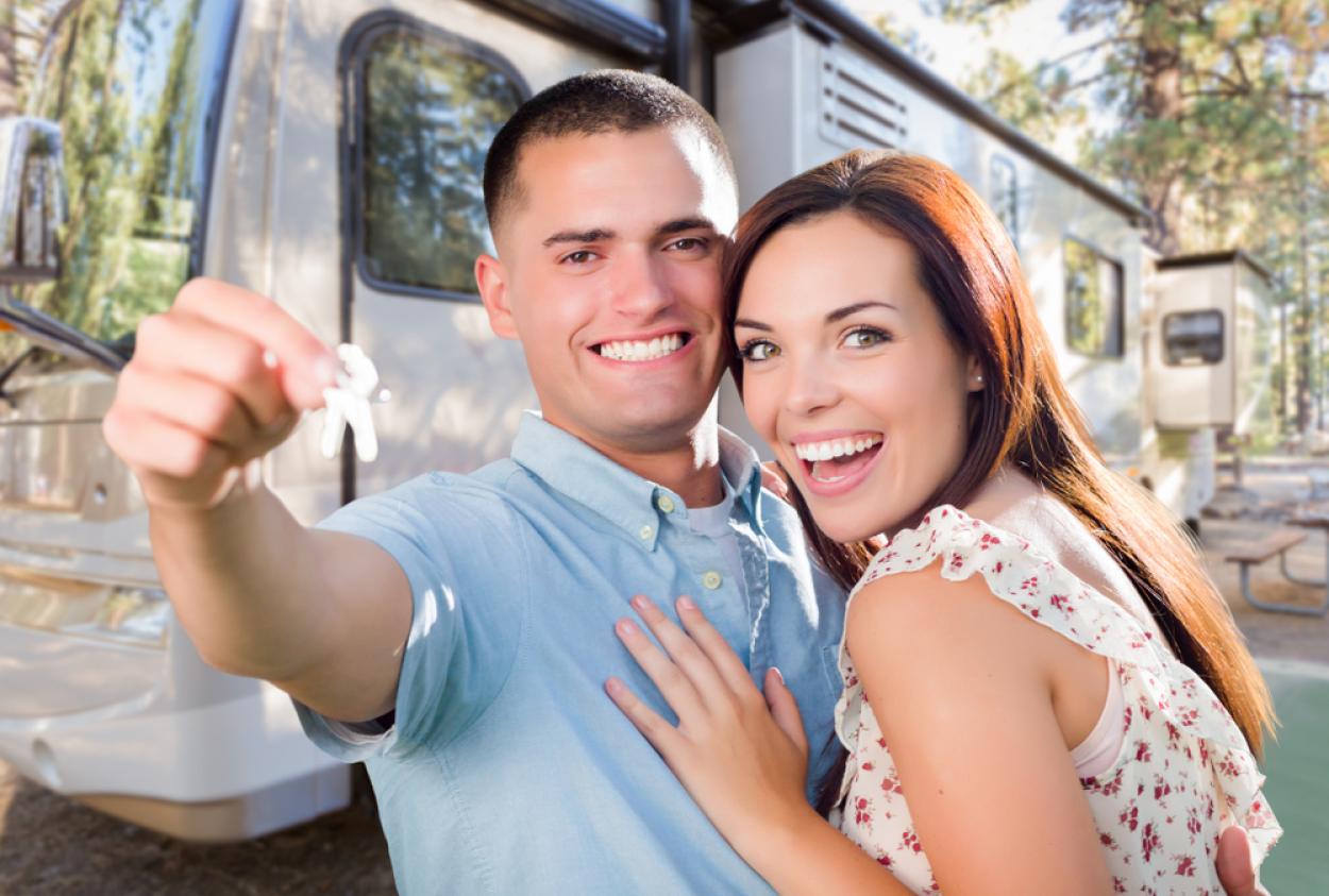 Couple holding keys in front of an RV