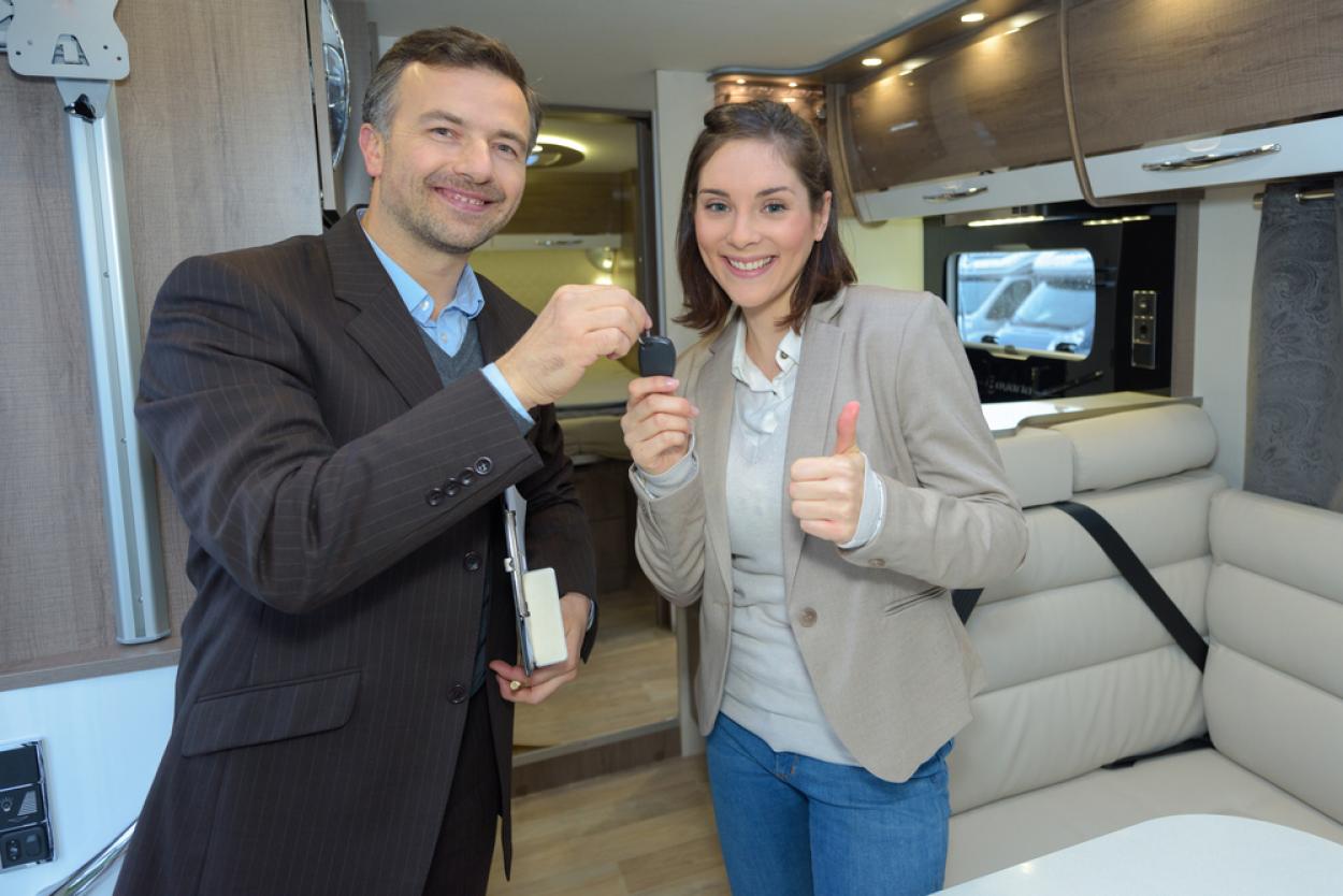 Woman and man standing in an RV exchanging keys
