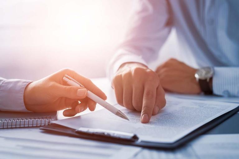 Two people's hands as they go over a contract