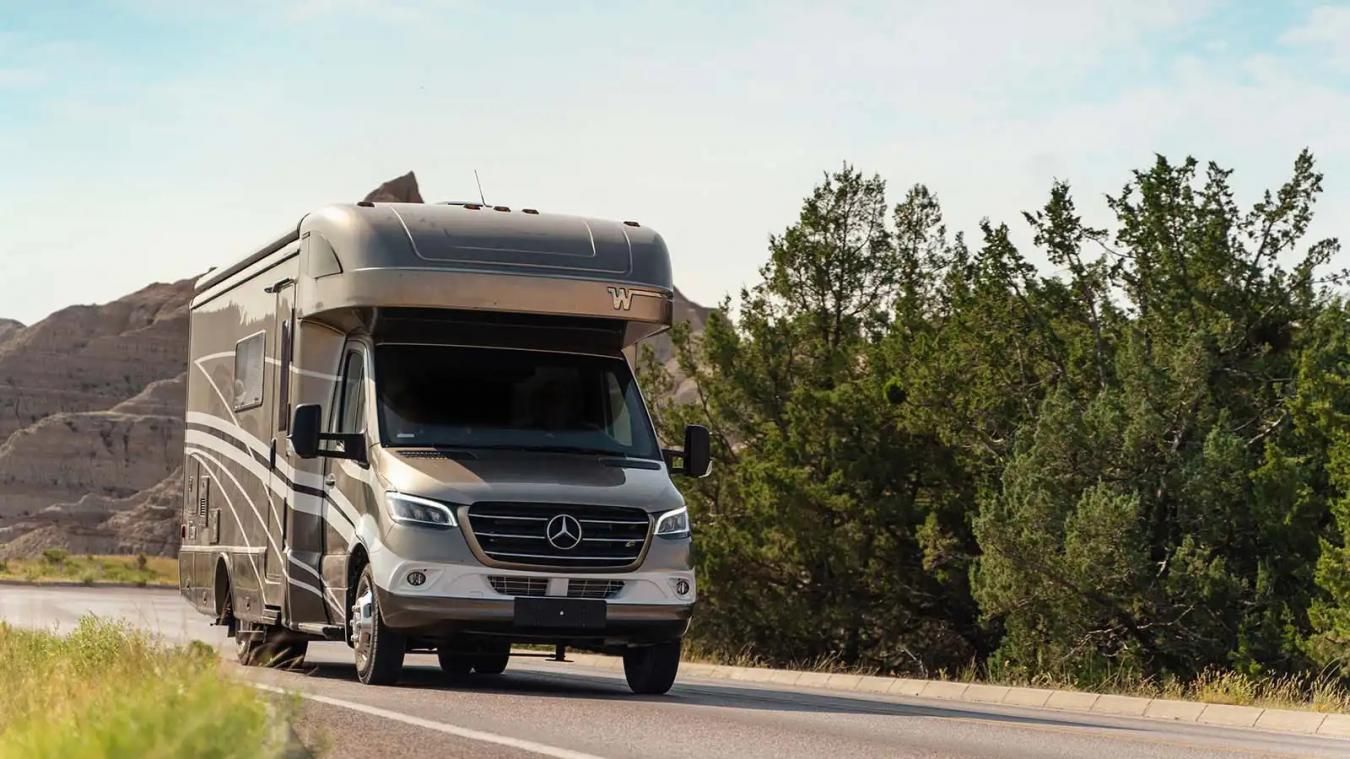 Winnebago RV driving along a forest