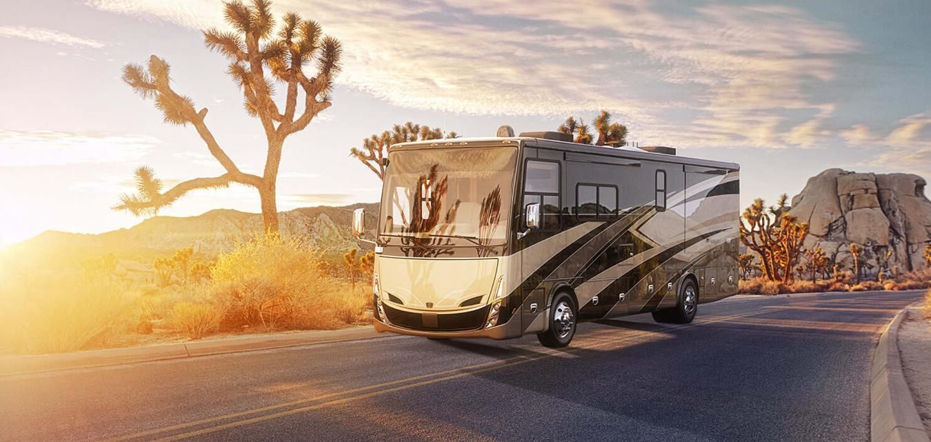 An exterior shot of a Tiffin RV driving along a desert sunset