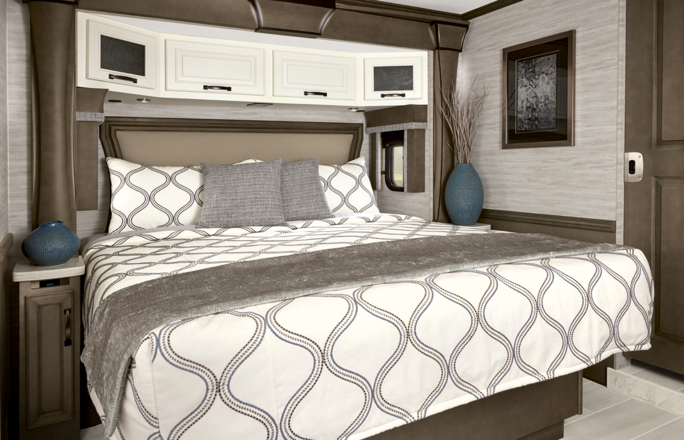 King-sized bed with white coverlet inside an RV