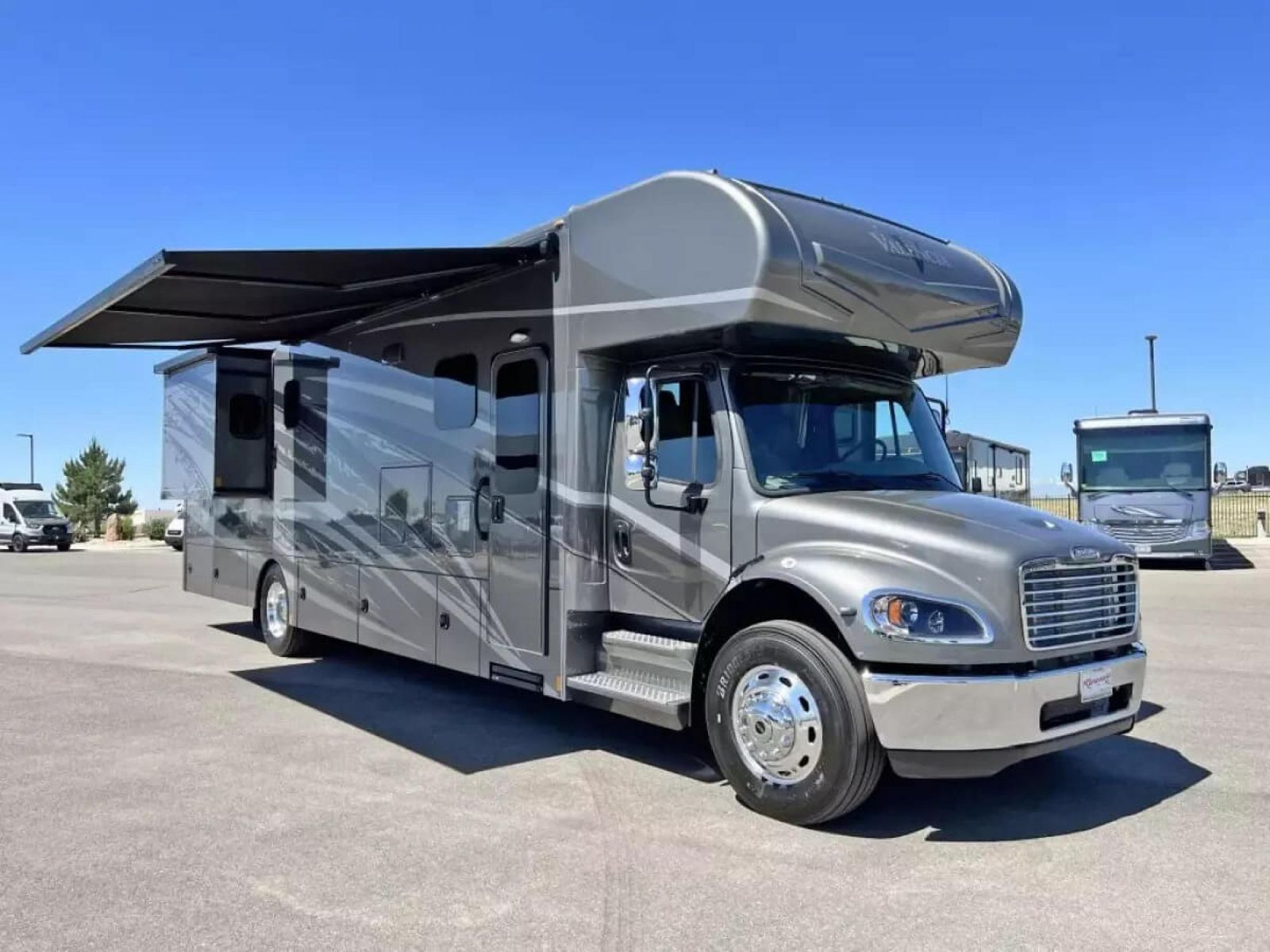 Gray Renegade Super C RV parked in a parking lot with awning extended