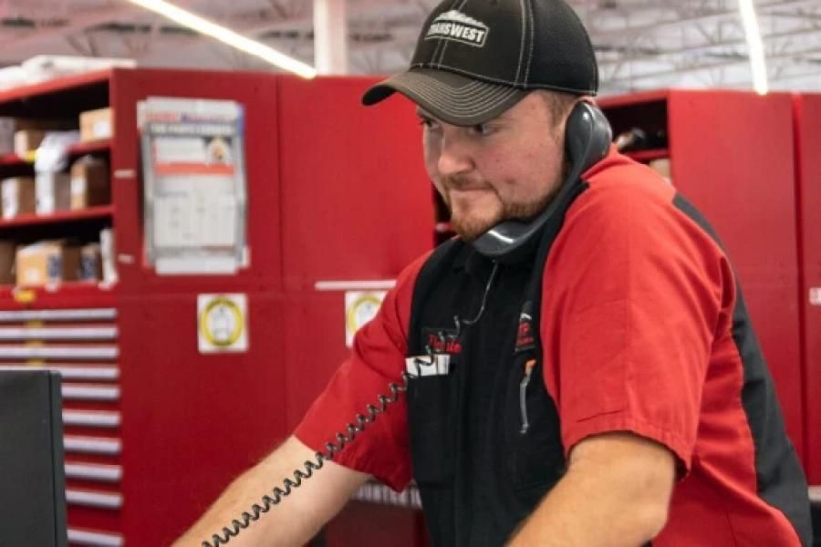 A Transwest employee in a red and black shirt talking on the phone