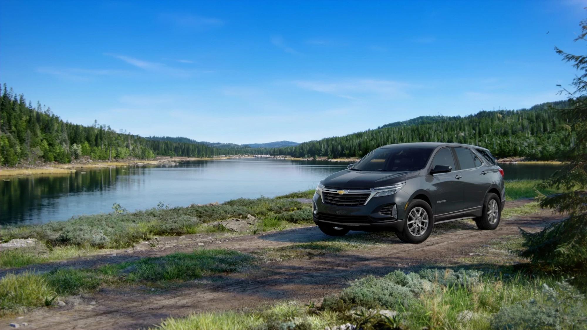 A sleek black Chevrolet SUV on a dirt road in front of a lake