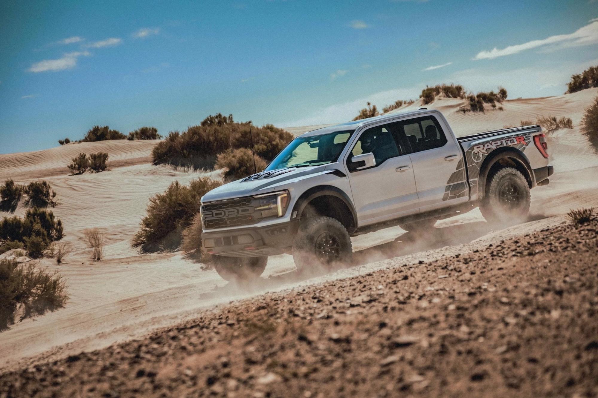 White Ford pickup truck with the Raptor label on the side on a desert environment