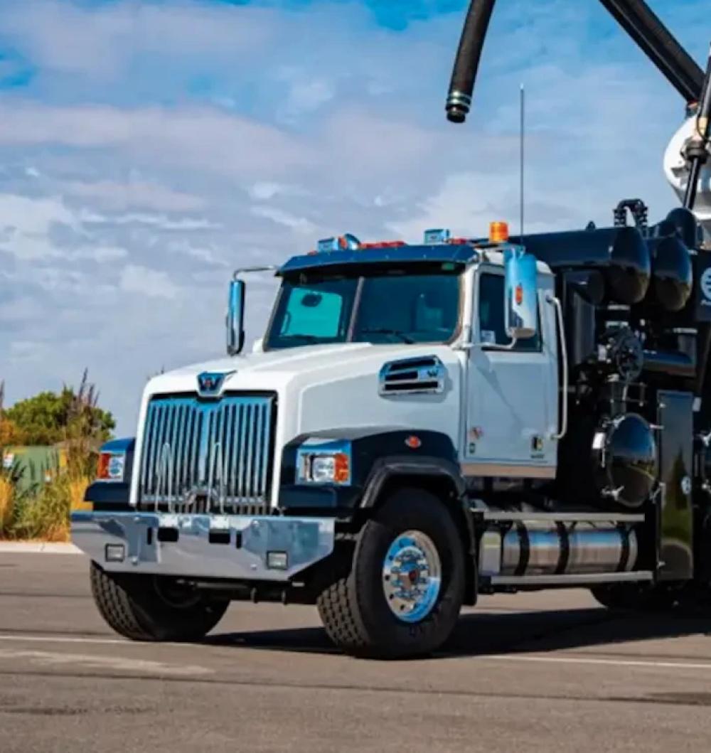 The front three quarter view of a black and white hydrovac truck