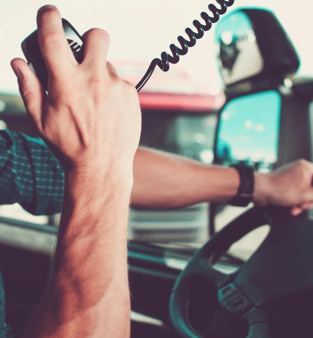 A driver holding and speaking into a CB radio microphone